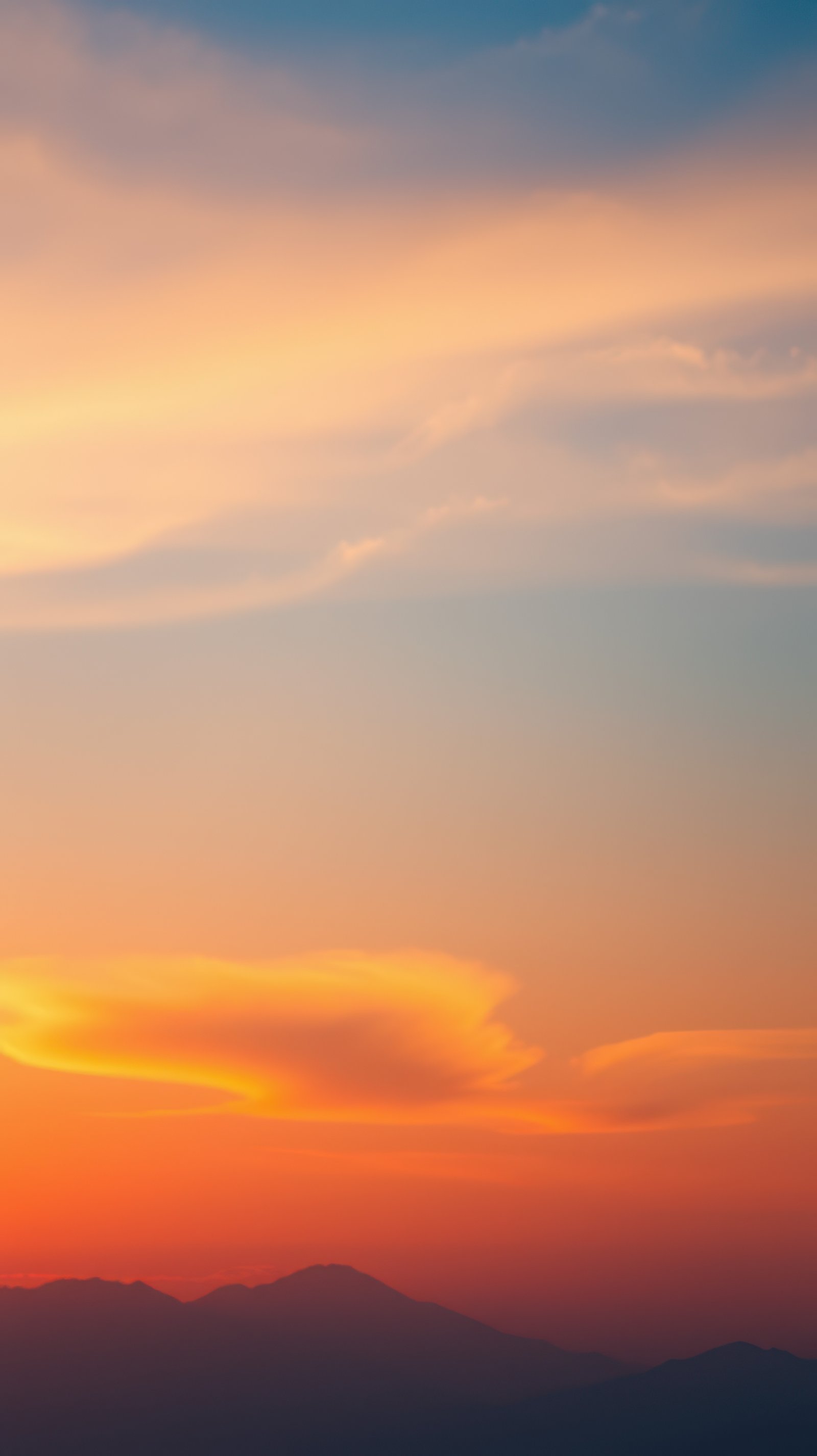 Vibrant sunset over mountains with clouds creating a stunning evening sky